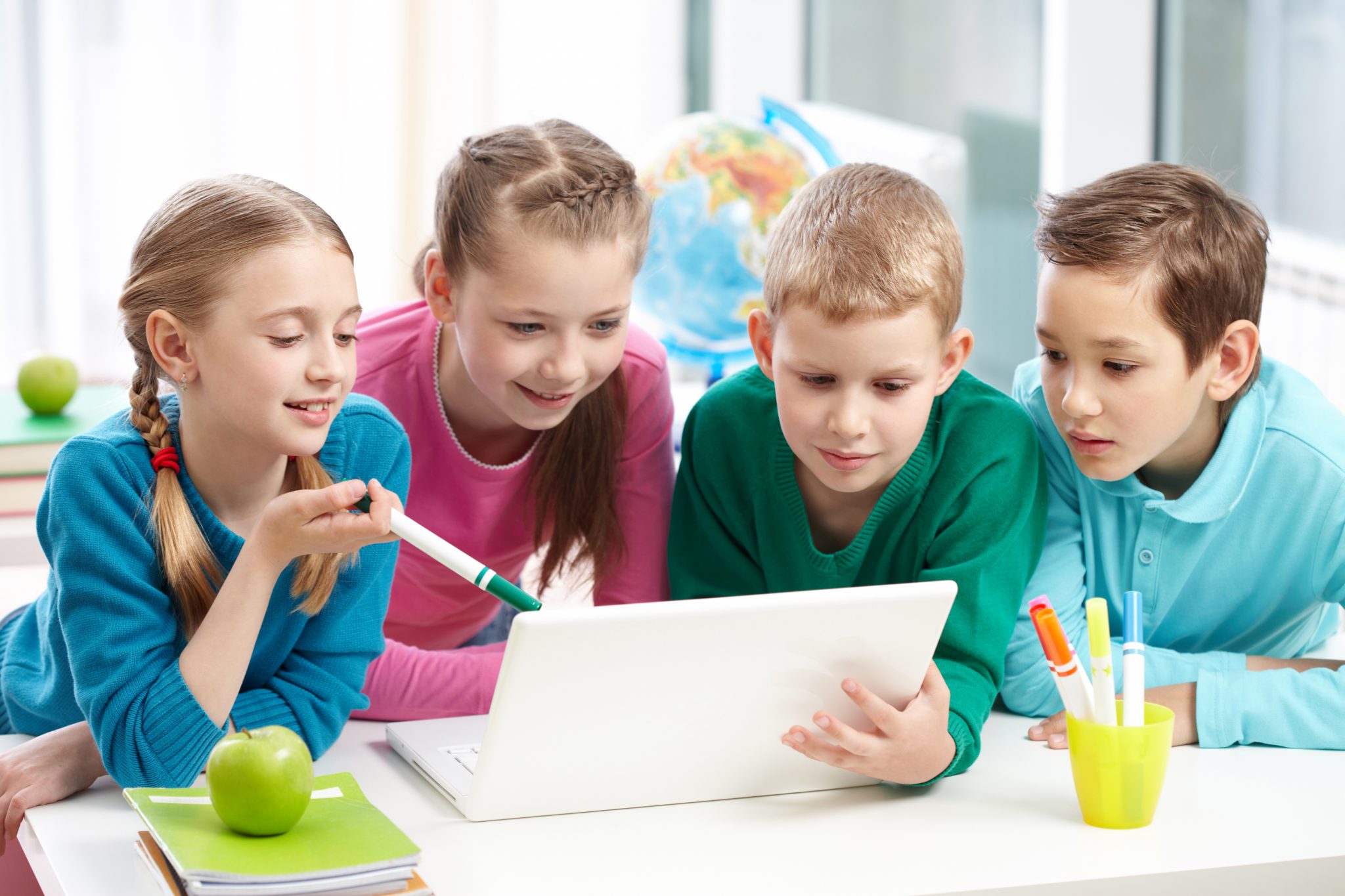 Niños y niñas de una clase observando su dispositivo y trabajando de forma colaborativa